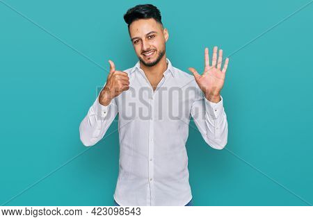 Young arab man wearing casual clothes showing and pointing up with fingers number six while smiling confident and happy. 