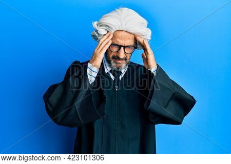 Middle age hispanic man wearing judge uniform with hand on head, headache because stress. suffering migraine. 