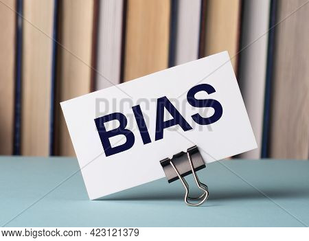 A White Card With The Text Bias Stands On A Clip For Papers On The Table Against The Background Of B