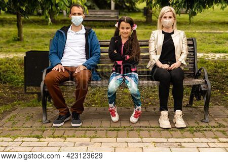 Woman And Man In Social Distancing Sitting On Bench In Park