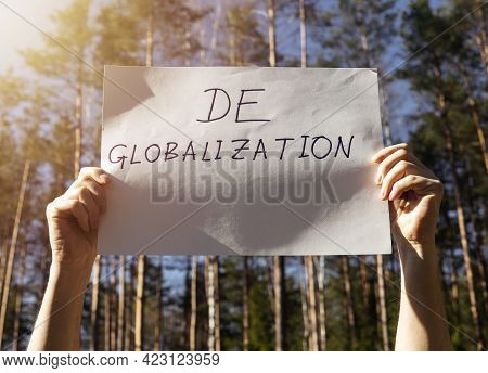 Deglobalization And Reverse Globalization Concept. Word On Paper Poster In Male Hands With Forest Ba