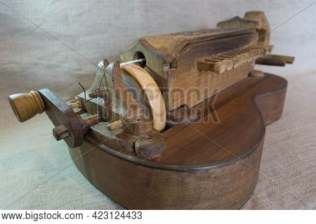 Vintage Wooden Homemade Musical Friction Instrument Hurdy-gurdy With A Guitar-shaped Body Lies On A 