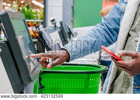 The Finger Of An African Man In Close-up At The Supermarket Checkout Selects The Desired Product On 