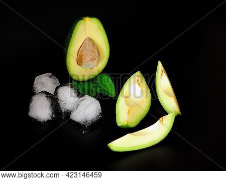 Pieces Of Ripe Avocado And Cubes Of Melted Ice On A Black Background.