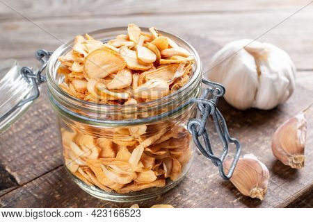 Fragrant Dry Garlic In Flakes In A Glass Jar On An Old Wooden Background