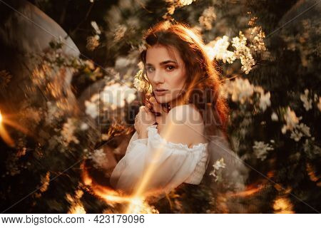 Portrait Of A Romantic Girl, Like A Forest Fairy, In A Blooming Garden With Elements Of Phantasmagor