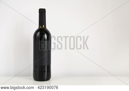 Black Bottle Of Red Wine On A White Background With Copy Space. Wine Mockup On The Table.