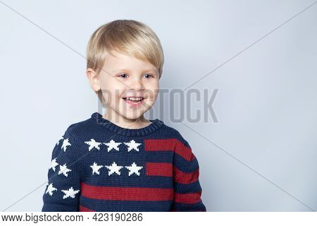 Smiling Kid In Sweater With Usa American Flag On White Background With Copy Space.
