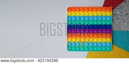 Top View Rainbow Silicone Toy Antistress Pop It On Colorful Background. Popular Children Toy Sensory