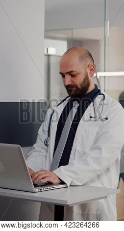 Close Up Of Surgeon Doctor Wearing Medical Uniform Typing Recovery Treatment On Laptop For Sick Woma