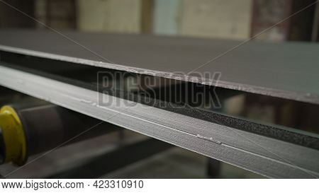 Continuous Sheet Of Metallic Material Being Fed Through Machine. Metal Sheet On The Conveyor. Painti