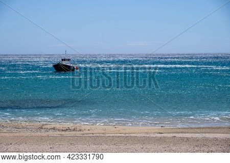Greece, Cyclades. Traditional Boat Anchored On Blue Color Sea Water