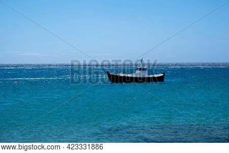 Greece, Cyclades. Traditional Boat Anchored On Blue Color Sea Water