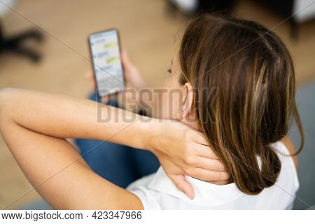 Woman With Neck Pain Sitting Using Mobile Phone