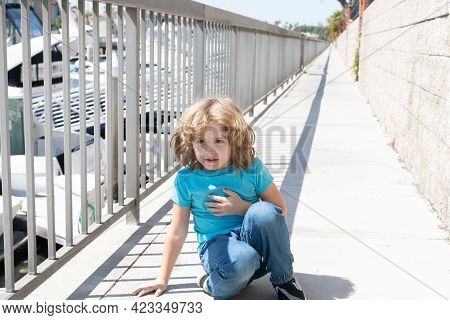 Paused For Breath. Boy Relax Hunkering Down On Promenade. Boy Child Take Short Rest