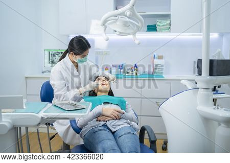 Asian Female Dentist Adjust Dental Surgical Light Then Start Checking Or Examining Tooth Of Young Gi