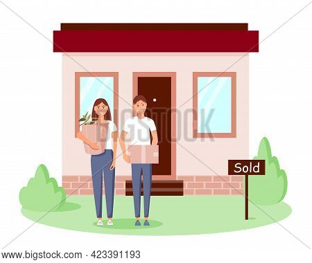 A Happy Young Family Bought A New Home. A Man And A Woman Are Standing With Boxes Near Their House. 