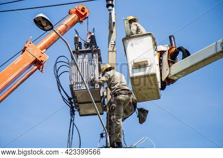 Nonthaburi, Thailand- May 19, 2021: Electrical Wireman Are  Installing The Transformer To A Light Po