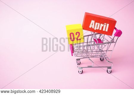 April 2nd. Day 2 Of Month, Calendar Date. Close Up Toy Metal Shopping Cart With Red And Yellow Box I