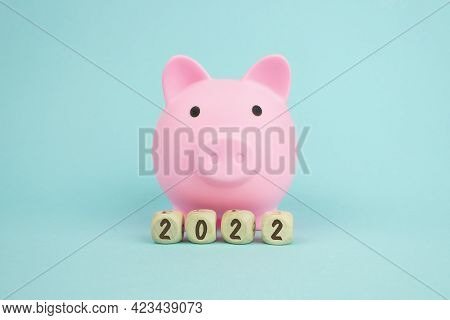 Pink Piggy Bank With Geometric Wood Blocks Cube Adt Text 2022 On Blue Background, Concept Of Savings