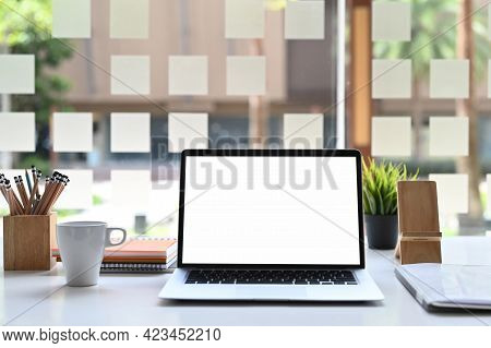 Laptop Computer With Blank Screen And Office Supplies On Workspace Table.
