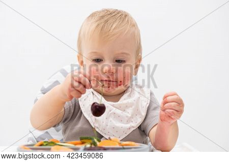 Cute Caucasian Baby About 1 Year Old, Eating Fresh Vegetables At High Chair. Self-feeding For Kids. 