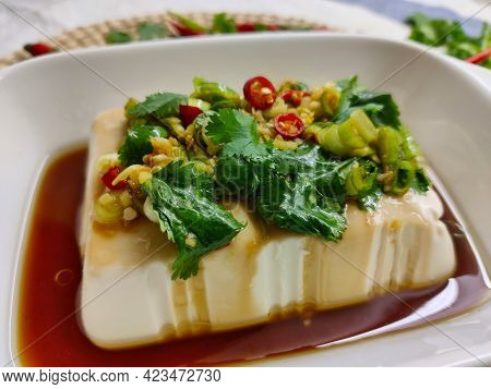 Silken Tofu Prepared In Soy Sauce With Coriander And Chili Pepper On Top Of It. It's Served In White