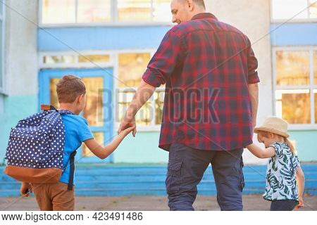 Father Accompanies The Children To School. A Man With His Son And Daughter Removed From The Back. A 