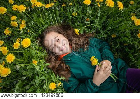 Close-up Of Happy Little Russian Girl With Her Hair Loose And With Smile, With Bouquet Of Dandelions