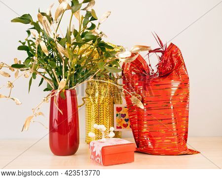 Gifts In Modern Wrappage With Mistletoe In Red Vase