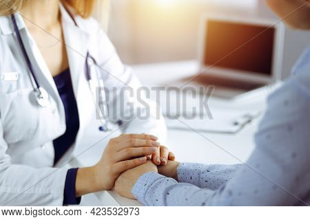 Unknown Woman-doctor Is Holding Her Patients Hands, Discussing Current Health Examination, While The