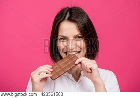 Beautiful Young Woman Bites A Bar Of Chocolate.