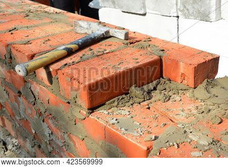 Masonry Tools And Equipment. A Close-up Of A Masonry Wall Construction Using A Bricklayer's Hammer, 