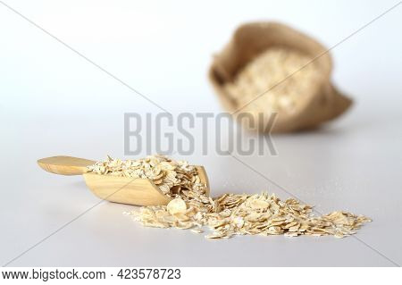 Oat Flake In A Sack And Spoon On The White Background. Heap Of Oats For Package Of Oatmeal Or Granol