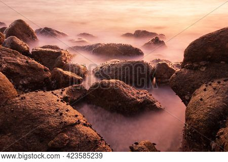 A Slow Shutter Shot Of The Sea Current With The Surrounding Rocks In The Evening.