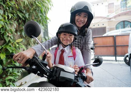 Mother Taking Her Daughter To School By Motorcycle In The Morning