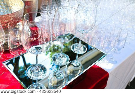 Three Crystal Wine Glasses On Mirrored Surface With Many Glasses Behind. Catering Service. Wine Tast