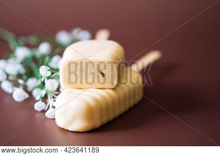White Chocolate Popsicles Cut With Filling Lying On Top Of Each Other On Brown Background