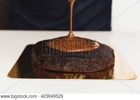 Chef Pouring Ganache On Top Of Chocolatecake
