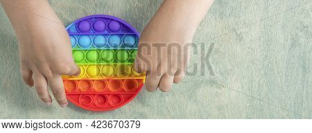 Banner With Boy Pressing On Colorful Rainbow Squishy Soft Silicone Bubbles. Kid Playing With Pop It 