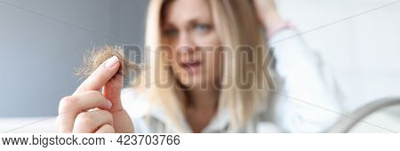 Frustrated Woman Holds Bun Of Her Hair In Her Hand