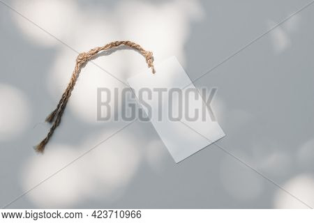Close-up Of Paper Gift Tag, Price Label With String Of Sisal Trope On White Table Background In Sunl