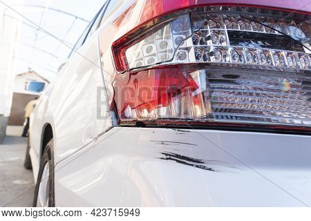 Big Black Scratch On Rear Bumper And Broken Taillight On White Car Due To Car Crash, Unsafe Driving,