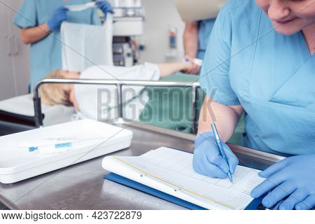 Nurse writing pre surgery report on file