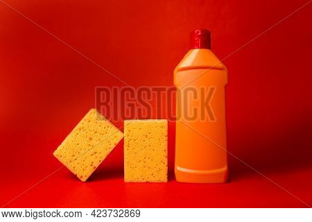 Yellow Sponge And Orange Bottle With Cleaning On A Red Background