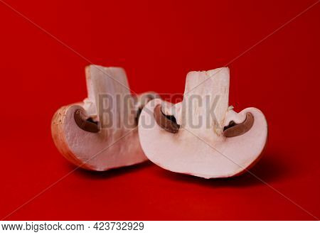 Two Mushrooms Of Mushrooms In A Cut On A Red Background.