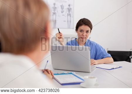 Portrait Of Medical Specialist Physician Nurse Discussing Sickness Examination With Doctor Sitting A
