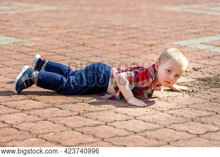 Cute Toddler Boy Fell On Park Road And Watching At The Camera