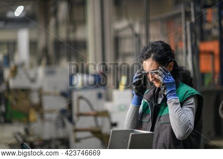 Woman worker wearing safety goggles control lathe machine to drill components. Metal lathe industrial manufacturing factory