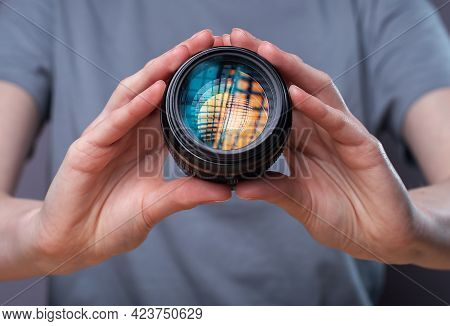 Digital Camera Lens With Beautiful Studio Softbox Reflecting In Hands Of Female Photographer.
